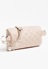Prošívaná béžová kabelka s hladkým povrchem, zlatým řetízkovým popruhem a kovovými štítky. Má válcový tvar se zipem a akcenty.
