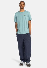Lysblå bomulds T-shirt med rund hals, parret med marineblå, løstsiddende cargo-bukser. Sneakers med grå og sorte accenter.
