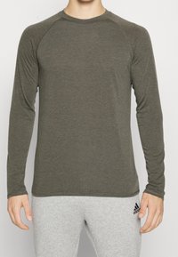 Langarmshirt in dunkelolivgrün, aus einem weichen, strukturierten Stoff mit Rundhalsausschnitt und Raglanärmeln. Keine auffälligen Muster oder Akzente.