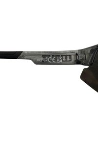 Gafas de sol con un marco negro transparente, que cuentan con un agarre texturizado negro en los brazos, y detalles de marca y certificación grabados en el costado.