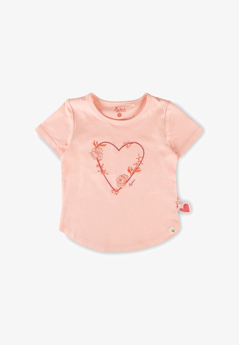 Chemise pour tout-petit à manches courtes rose clair avec une silhouette de cœur floral brodée en orange sur le devant et une petite étiquette en tissu en forme de cœur sur le côté.