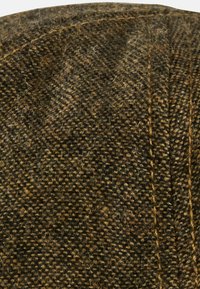 Braune und beige Tweedkappe mit strukturierter Oberfläche, Fischgrätmuster und genähten Details entlang der Nähte.