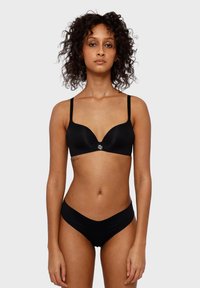 Zwart lingeriesetje met een gepolsterde bh met een diep uitgesneden decolleté en verstelbare bandjes, gecombineerd met bijpassende hoog uitgesneden slipjes.