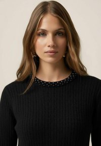 Pulover negru din tricot cu dungi, cu decolteu rotund decorat cu detalii din mărgele negre. Textură netedă, croială care se mulează pe corp.