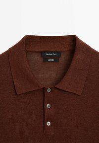 Polo shirt in lino marrone con colletto classico, patta a tre bottoni e lavorazione a maglia testurizzata. Etichetta del brand visibile all'interno del colletto.