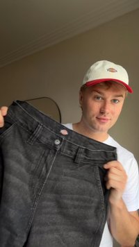Juodi džinsai iš džinsinio audinio su mygtuku ir užtrauktuku, turintys penkias kišenes ir nežymų nudėvėjimą. Ant liemens matyti logotipo etikettė.