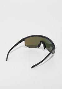 Sonnenbrille mit schwarzem Rahmen und achteckigen, grün getönten Gläsern. Schlanke Bügel und minimales Zubehör unterstreichen das schlanke, sportliche Design.