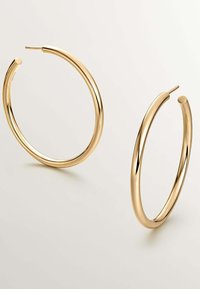 Pendientes de aro de oro con un acabado suave y pulido. Diseño circular con un perfil ligero y delgado. Cierre abierto en la parte superior.
