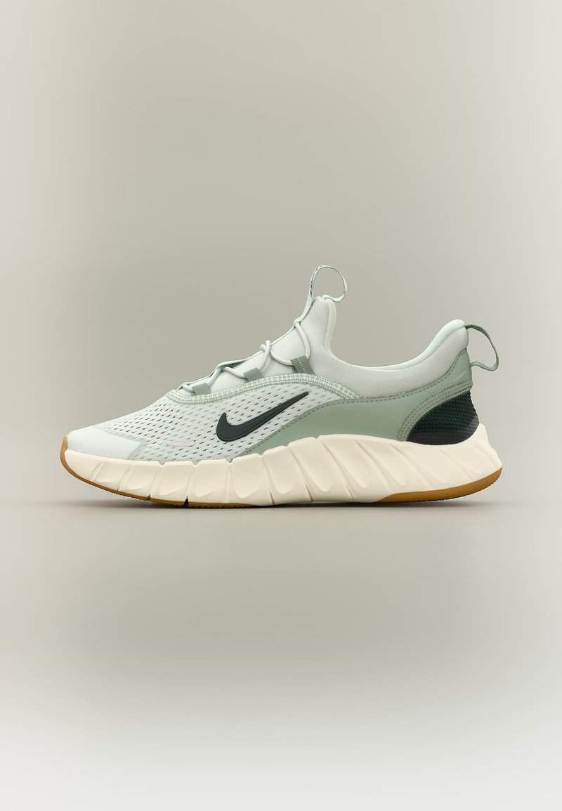 Ανοιχτό γκρι αθλητικό παπούτσι Nike με μαύρο σήμα swoosh, υφασμάτινο επάνω μέρος με υφή, παχιά λευκή σκαλιστή σόλα και ταινίες τραβήγματος στη γλώσσα και στη φτέρνα.