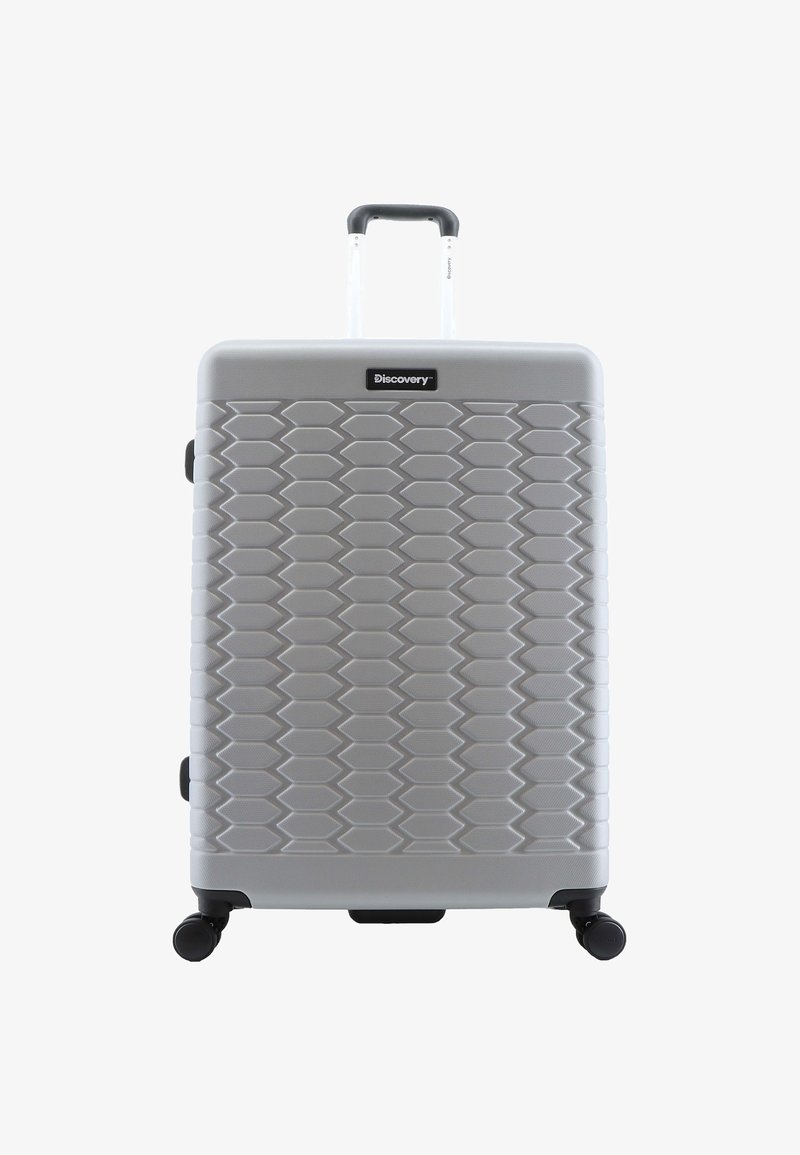Hard-shell suitcase in silver with a textured hexagonal pattern. Features a retractable handle and four black swivel wheels for mobility.
