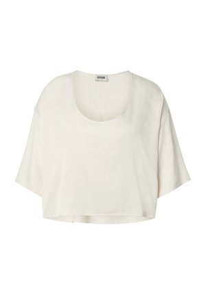 Blouse courte crème à manches courtes, coupe ample, col rond, en tissu léger, étiquette DRYKORN sur le col.