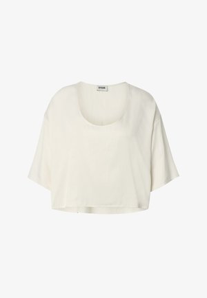 Blouse courte crème à manches courtes, coupe ample, col rond, en tissu léger, étiquette DRYKORN sur le col.