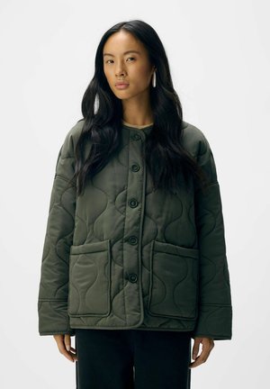 Veste matelassée verte avec un col rond, des boutons sur le devant et deux grandes poches. Présente une texture ondulée et une coupe décontractée.