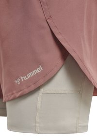 Pantalones cortos en tela color rosa polvo con un diseño en capas, que presenta un tono gris claro debajo. Incluye el logo "hummel" en blanco y detalles visibles de costura.