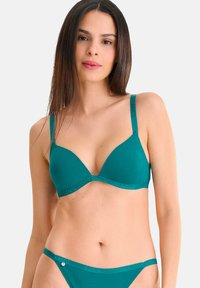 Soutien-gorge turquoise au design triangulaire lisse avec des bretelles réglables ; présente un logo discret le long de la bande. String bikini assorti présenté.