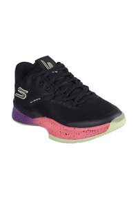 Zapatilla deportiva negra con parte superior de malla transpirable, entresuela moteada en púrpura y rosa, y suela verde translúcida. Cuenta con diseño de cordones.