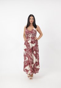 Robe maxi avec imprimé feuilles bordeaux sur fond crème, bretelles spaghetti réglables, taille smockée et ourlet à volants en étages.