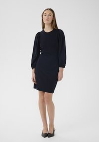 Rochie bleumarin cu mâneci lungi bufante. Confecționată dintr-un material moale, are un decolteu simplu rotund și o siluetă ajustată.