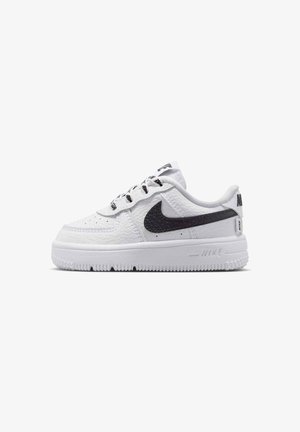 Baskets basses blanches Nike en cuir texturé, logo swoosh noir, semelle blanche et lacets avec accents noirs sur fond blanc.