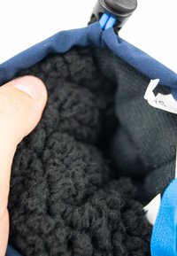 Extérieur en tissu bleu avec un doublage en velours noir. Gros plan montrant la texture intérieure et un doigt tenant le bord. Contient une étiquette.