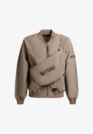 Beige Bomberjacke mit Reißverschluss, gerippten Bündchen und Kragen, dazu eine passende Umhängetasche mit schwarzem Aufdruck "KHUJO 2001".
