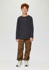 Ciemnoszara koszula z długim rękawem z napisem "EASY MINDSET", w połączeniu z beżowymi spodniami typu cargo i jasnymi sneakerami, stojąca na jednolitym tle.