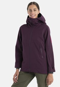 Fioletowa nieprzemakalna kurtka z wysokim kołnierzem, zamek błyskawiczny z przodu i bocznymi kieszeniami. Charakteryzuje się luźnym krojem i subtelnym Brandingiem na rękawie.