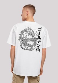 Weißes Baumwoll-T-Shirt mit einem großen schwarzen Drachengrafik und japanischem Text auf der Rückseite. Kurze Ärmel, lockerer Schnitt und Rundhalsausschnitt.