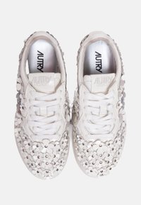 Zapatillas blancas de cordones con apliques florales elevados que cubren la puntera y los lados, plantillas metálicas plateadas y logo de la marca en la lengüeta.