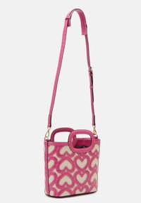 Rosa handväska med ett hjärt-mönster på en beige bakgrund, med slätt, strukturerat material och dubbla handtag. Justerbar axelrem ingår.