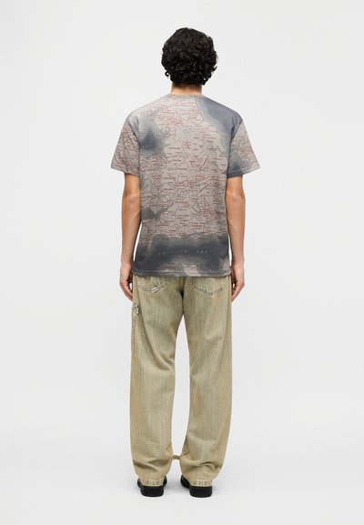 Κοντομάνικο γκρι μπλουζάκι με εκτύπωση χάρτη  σε κόκκινο, συνδυασμένο με ανοιχτόχρωμα, φαρδιά τζιν παντελόνια με λεπτομέρεια φερμουάρ.