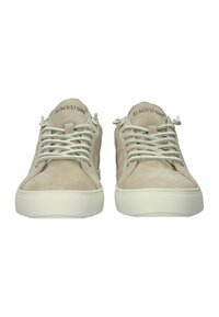 Beige suède sneakers met dikke witte zolen en bijpassende veters, met het merk "BLACKSTONE" op de tong, gezien van voren.