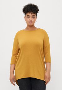 Mustard yellow, loose-fitting top with a Scoop neckline and three-quarter sleeves. Soft texture and curved hemline for relaxed style.