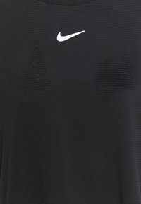 Camiseta deportiva negra hecha de tela texturizada. Presenta un logo blanco de Nike en el pecho y malla colocada estratégicamente para ventilación.
