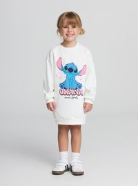 Abito oversize bianco con un personaggio dei cartoni animati blu con grandi orecchie, accompagnato dal testo "Ohana means family" in rosa e nero.