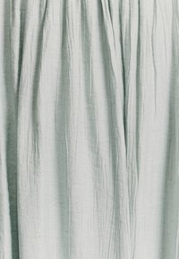 Šviesiai mėlynas lininis audinys su tekstūriniu paviršiumi, turintis vertikalias raukšles ir subtilų blizgesį, sukuriantis drapiruotą išvaizdą.