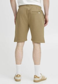 Lys brune sweatshorts med elastisk linning, sidelommer og en baklomme. Avsluttet med jevn søm og en glatt tekstur.