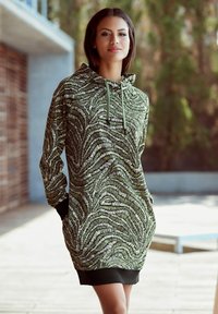 Grünes Kapuzenkleid mit welligem, strukturiertem Muster. Lange Ärmel, Fronttaschen und ein schwarzer Rippabschluss. Leichter Stoff.