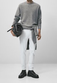 Grijze gebreide trui, witte denim broek, zwarte leren laarzen en een zwarte handtas met een zilveren sluiting. Eenvoudig, modern ontwerp; casual pasvorm.