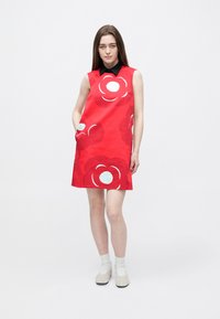 Červené šaty bez rukávov s veľkými bielymi a tyrkysovými kvetinovými vzormi, čiernym golierom, bočnými vreckami a priliehavým strihom. Jemná textúra látky.