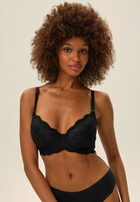 Czarny biustonosz na drutach z koronką, z falbaniastymi krawędziami i regulowanymi ramiączkami, o gładkiej fakturze i nakładce w kwiatowy wzór.