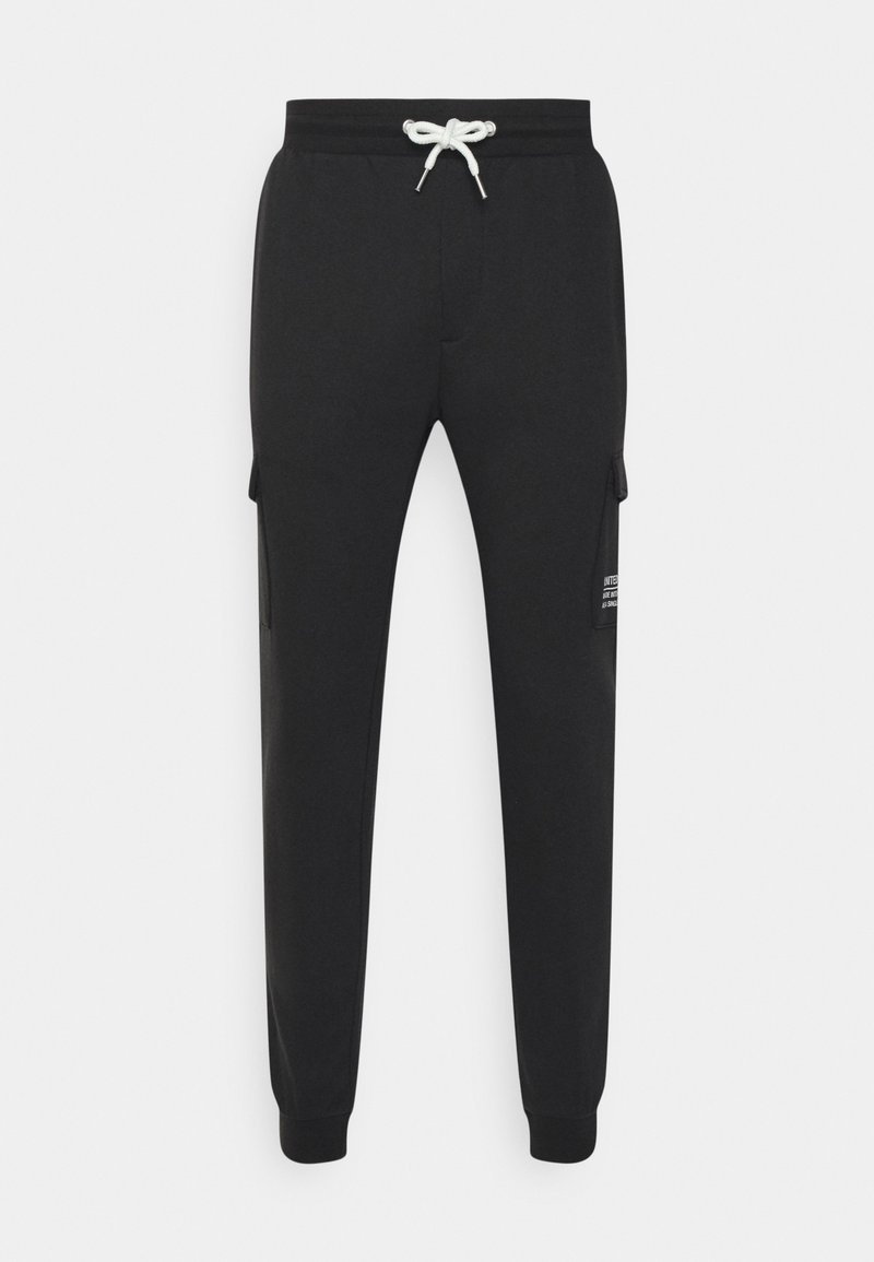 Pantalon de survêtement noir avec une taille élastique, un cordon de serrage et des poches cargo latérales. Texture lisse et poignets ajustés aux chevilles.