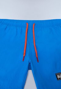 Modré plavky s elastickým pásom, s oranžovými šnúrkami a černou nášivkou na prednej strane. Hladký povrch, ľahký materiál.