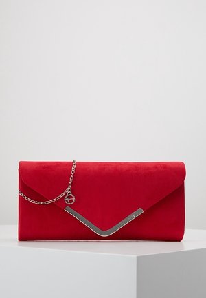 Clutch sobre de ante rojo con detalle en forma de V plateado y cadena, exhibido sobre un podio blanco contra un fondo liso.
