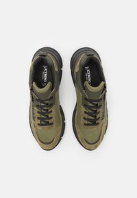 Olivi vihreät ja mustat ICEBERG-tennarit mustilla nauhoilla, tekstuuri-nahka- ja mokkatyöstöillä, kuvattu ylhäältä valkoista taustaa vasten.