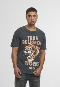 Pelēks kokvilnas t-krekls ar lielu, detalizētu oranžo un melno tīģera grafiku, zem kuras ir teksts "TRUE RELIGION TIGERS MFG".