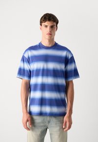 Camiseta de rayas azules con rayas horizontales en distintas tonalidades de azul, confeccionada en una tela suave, con cuello redondo y mangas cortas.