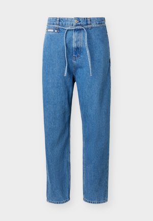 Kék farmernadrág egyenes szárú, magas derekú, elöl gombos, cipzáras, és a derekán vékony farmer övvel átkötve.