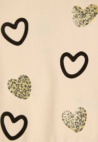 Tessuto beige chiaro con cuori contornati in nero e cuori di paillettes dorate. Presenta cuori di diverse dimensioni e textures su tutta la superficie.