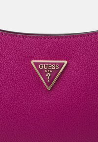 Fuchsia tekstureret lædertaske med et trekantet gul- og pink Guess-logo. Glat overflade med kontrasterende syninger som accent.